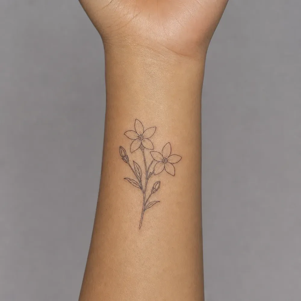 A small sampaguita sprig with two flowers and two buds tattooed on the inner wrist of light morena Filipino skin.