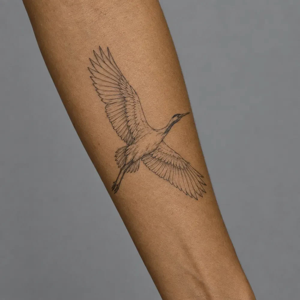 A fine-line crane in flight tattooed along the inner forearm of olive skin.