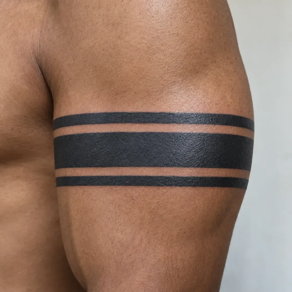 A three-stripe blackwork armband tattooed around the bicep of warm brown skin.