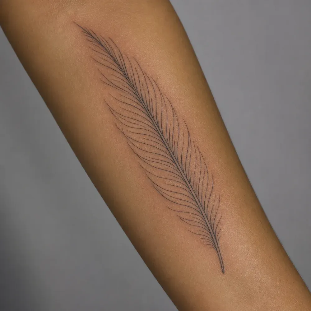 A long fine-line feather tattooed along the inner forearm of medium tan skin.