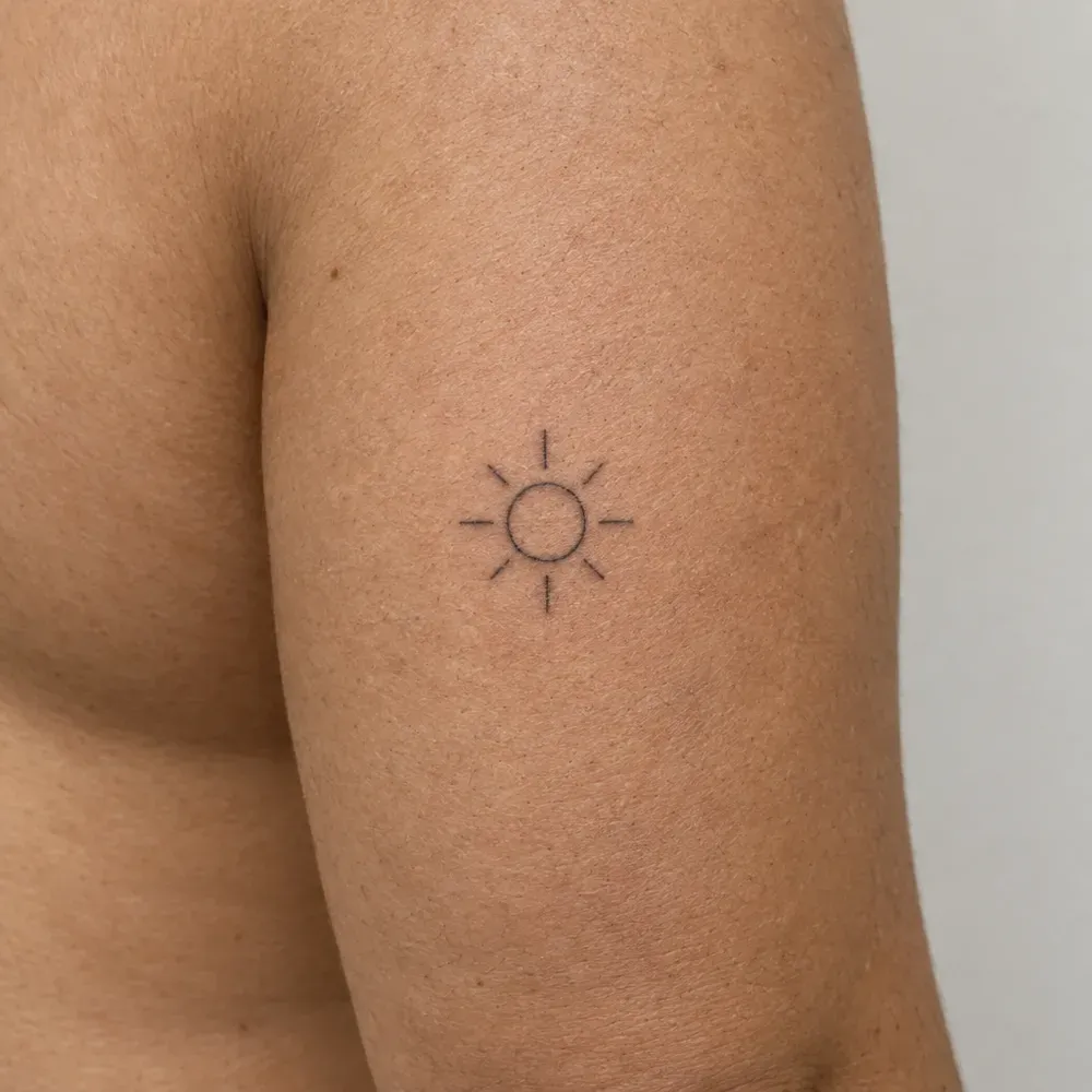 A small rayed sun tattooed on the back of an upper arm, olive skin.