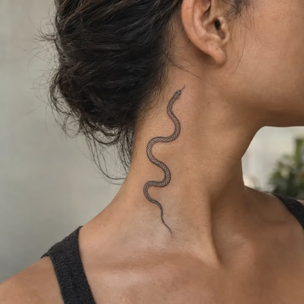 The fine-line snake tattooed down the side of a neck from below the ear toward the collarbone, on olive skin, the head turned away.