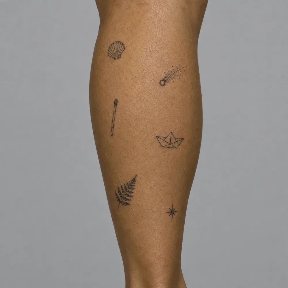 Six small separate tattoos scattered across a calf with bare skin between them, on olive skin.