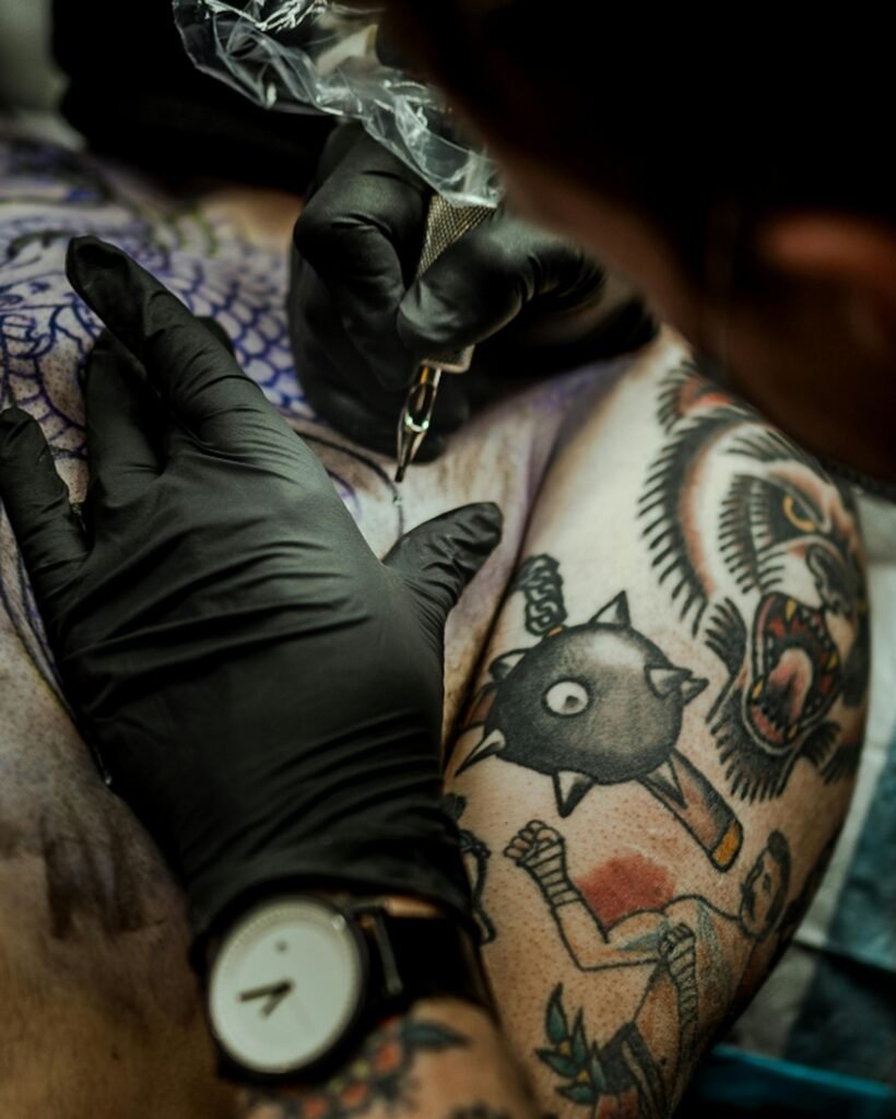 Tattoo artist creating a detailed design on a client's arm in a studio setting.